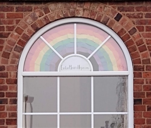 Paper rainbow and 'EasterMeansHope.com' in arched window
